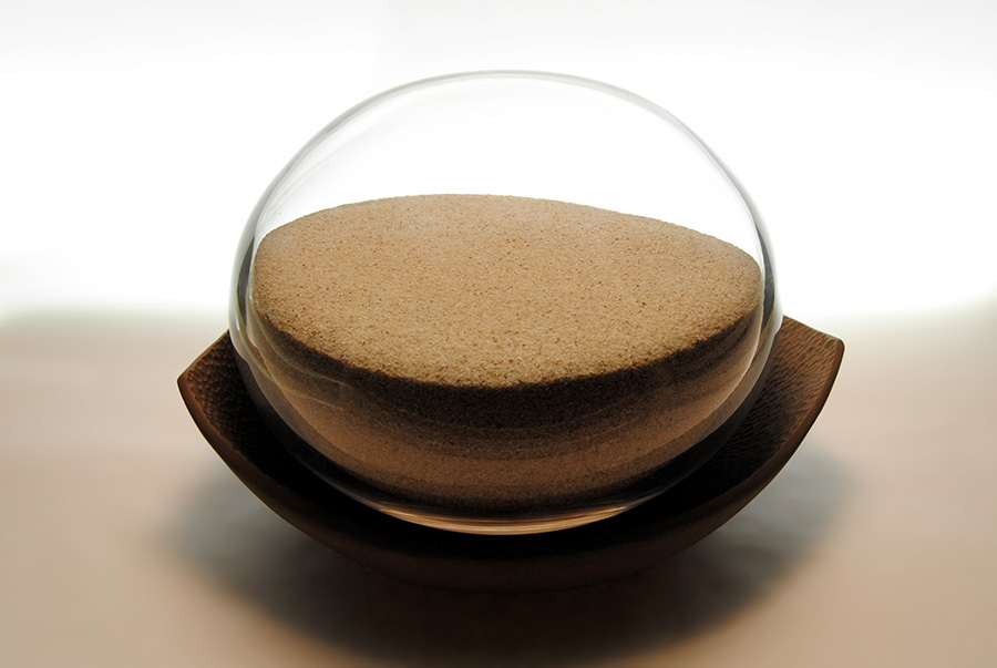 Urna furneraria para ceniza en vidrio soplado incoloro, cierre en madera y bandeja en barro negro esculpito.