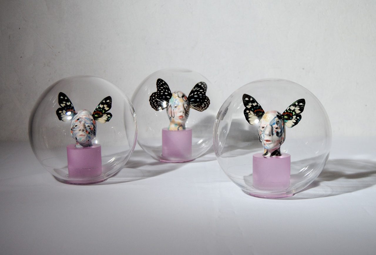 Escultura en vidrio de cabezas con alas de mariposa