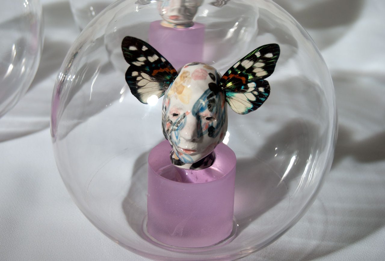 Escultura en vidrio de cabezas con alas de mariposa